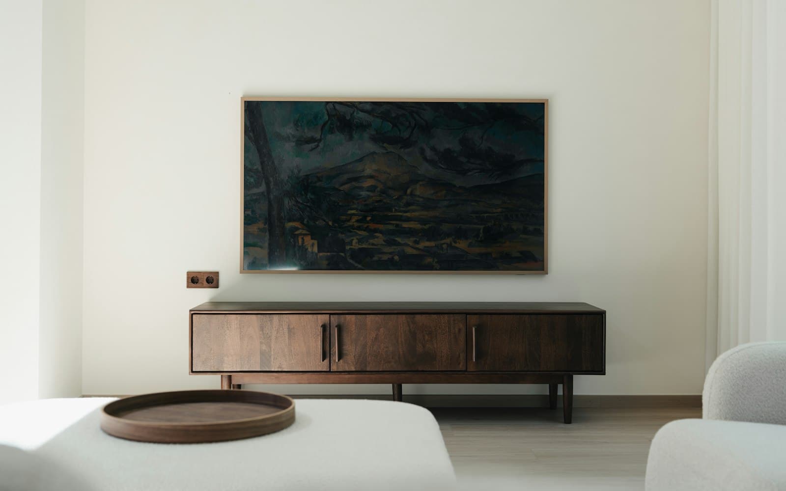 Slim art-mode Samsung Frame TV mounted flush on a wall, displaying a painting