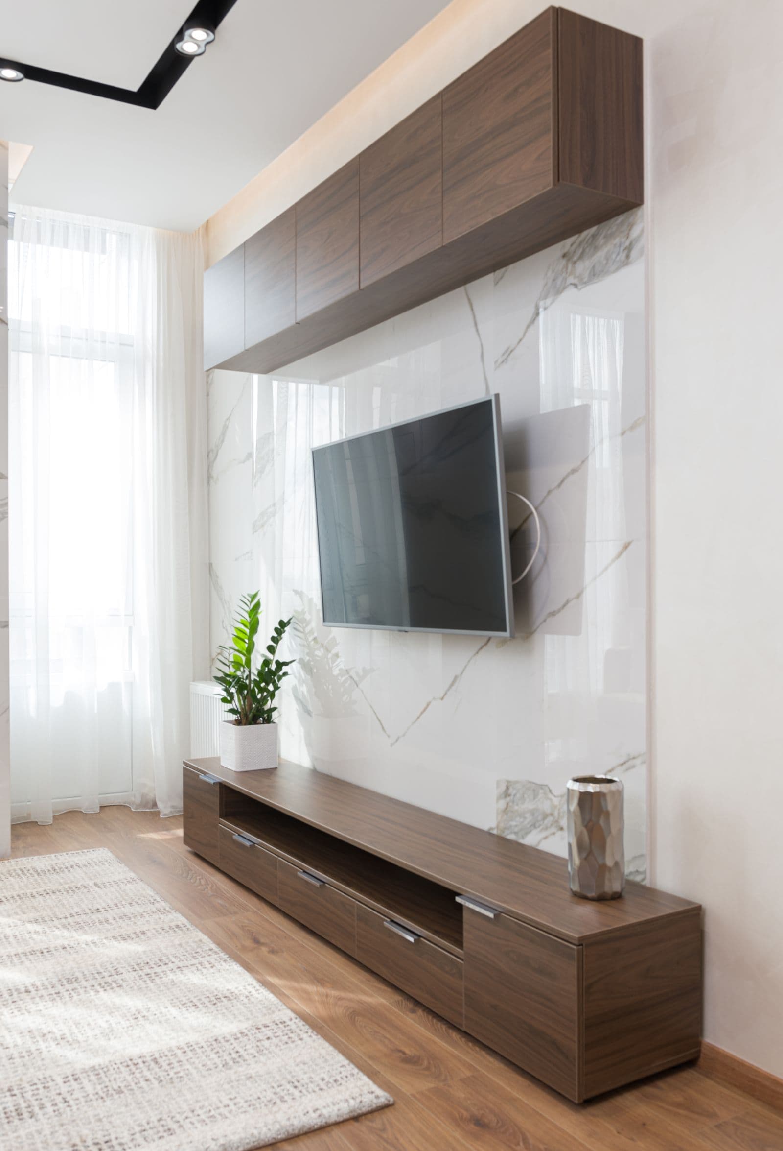 TV mounted on a swing-arm bracket against a marble accent wall, the kind of clean install we do in West University Place