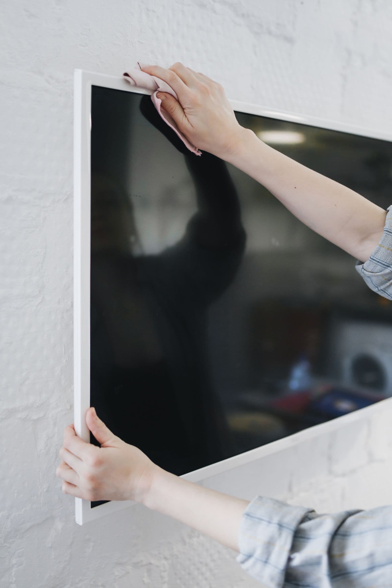 Flat-screen TV mounted flush on a white brick wall, typical of the rooms we plan TV mounting for in Memorial Heights