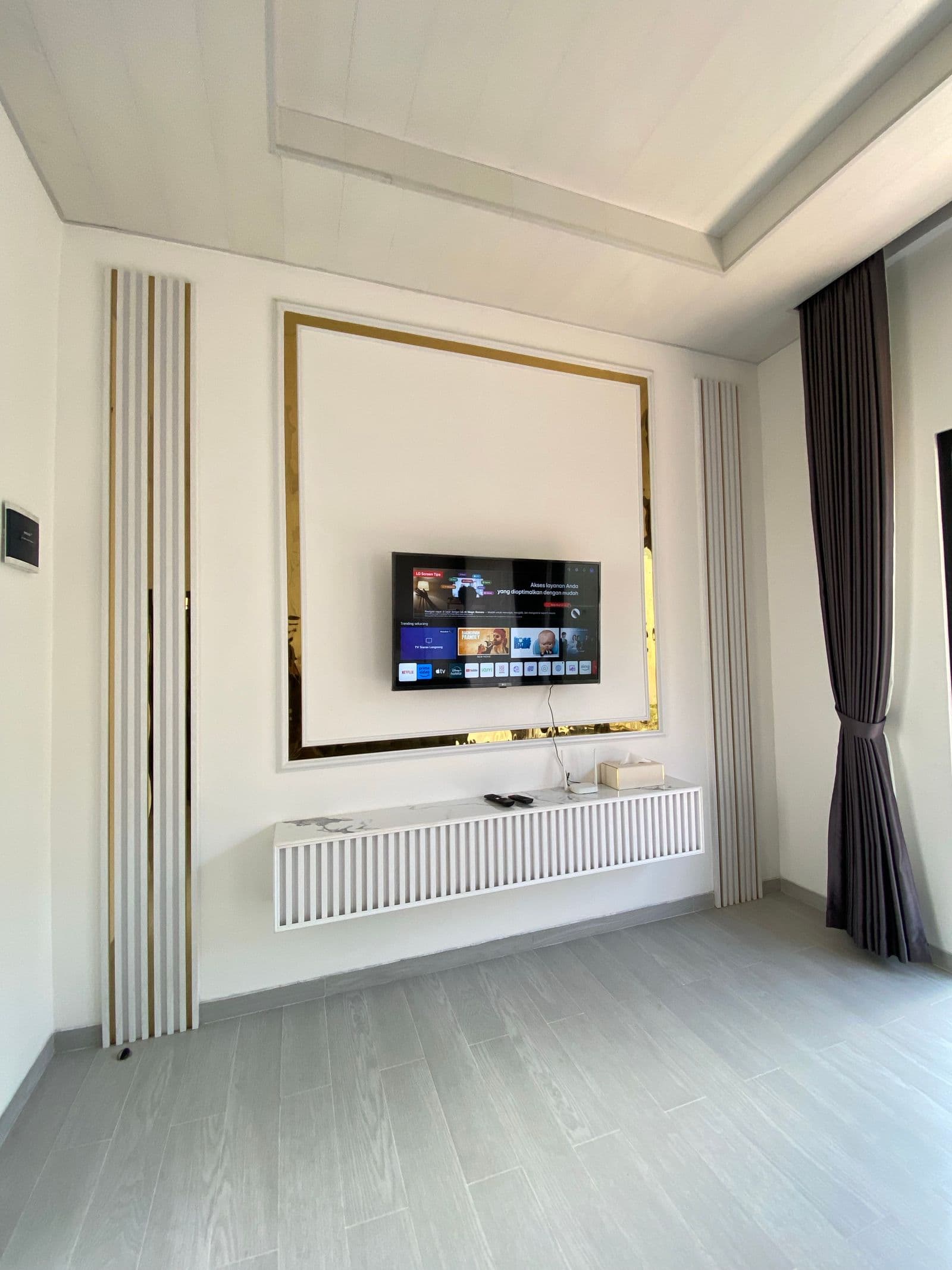 Flat-screen smart TV mounted flush on a wall inside a decorative gold-trimmed panel, cords fully hidden